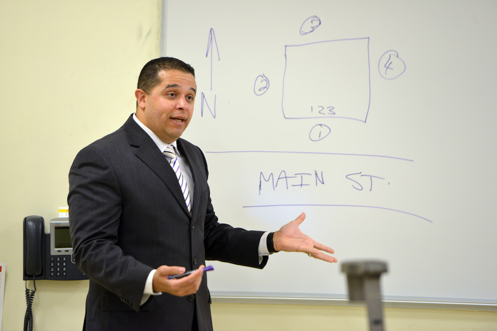 A criminal justice professor teaches in front of a map drawn on a whiteboard
